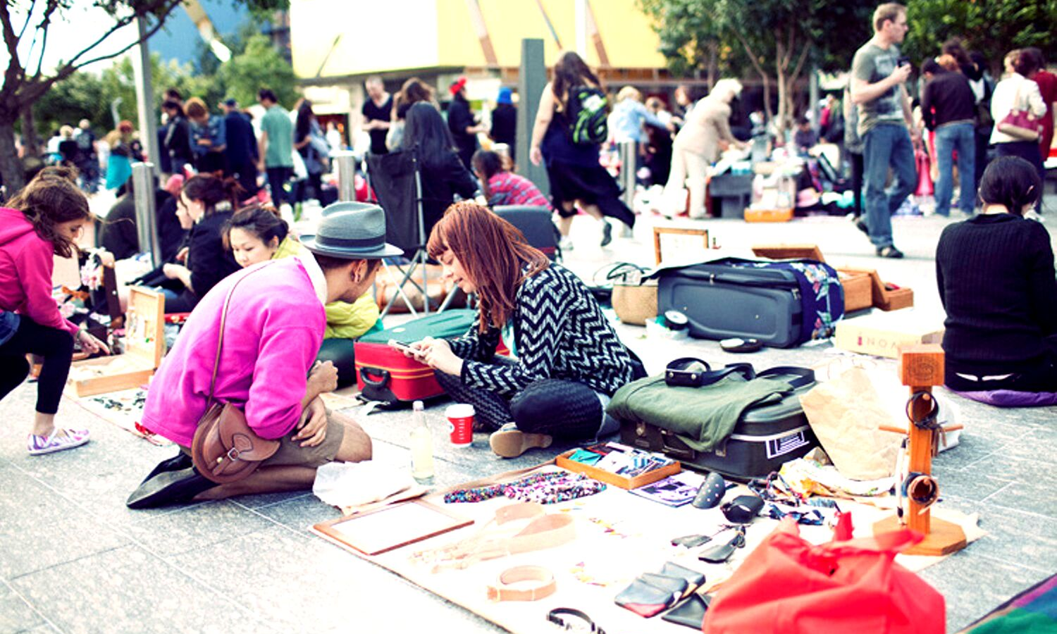 Market scene with lots of open suitcases. In this photo a woman is showing a customer some of her items for sale. 