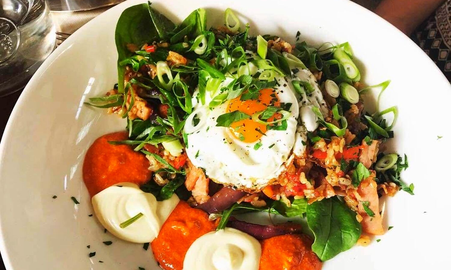 A picture of a typical brunch on a plate. Eggs, tomatoes and herbs. 